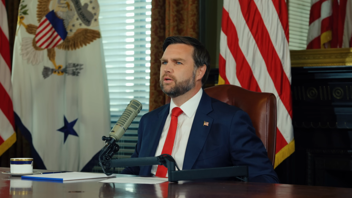 US Vice President JD Vance seated at a desk in front of flags