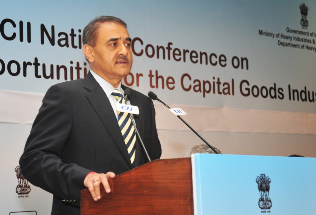 Praful Patel in a dark suit and striped tie speaking at a lectern