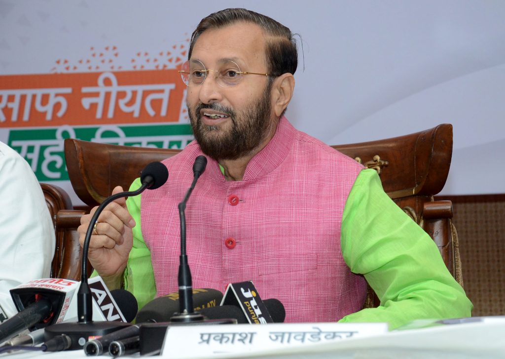 Prakash Javadekar in a pink kurta and green jacket speaking at press microphones