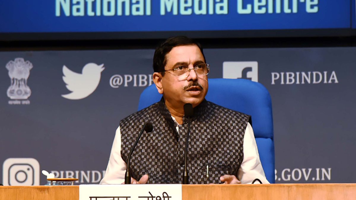 Pralhad Joshi in glasses and a patterned waistcoat seated at a press conference at the National Media Centre