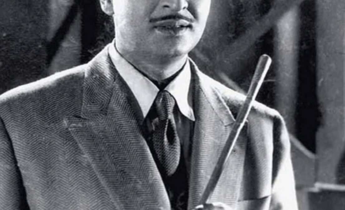 A black-and-white still of the young Pran in a hat and suit