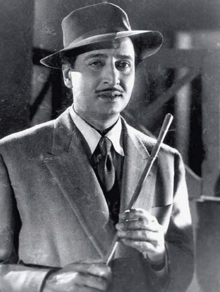 A black-and-white still of the young Pran in a hat and suit