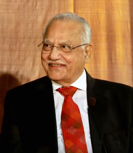 Prathap C. Reddy in glasses, a dark suit and a red tie