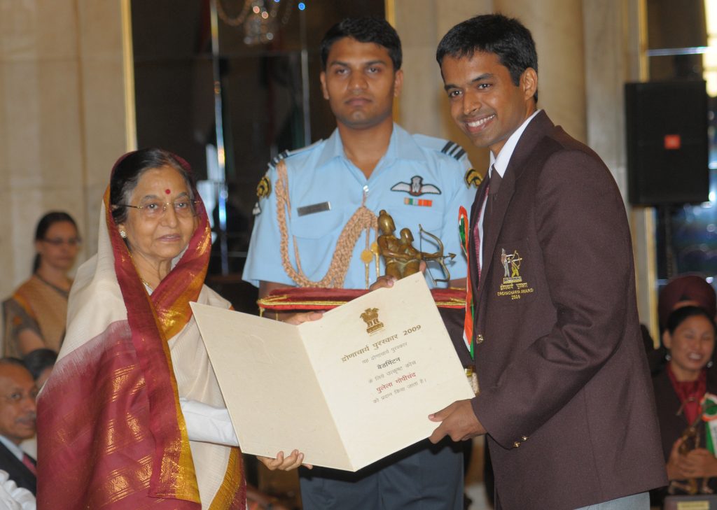 Pullela Gopichand in a dark blazer receiving the Dronacharya Award from President Pratibha Patil