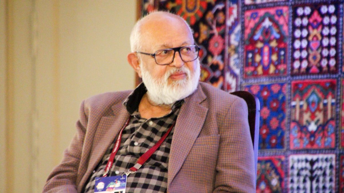 Pushpesh Pant with a white beard and glasses, in a checked jacket, seated at a festival