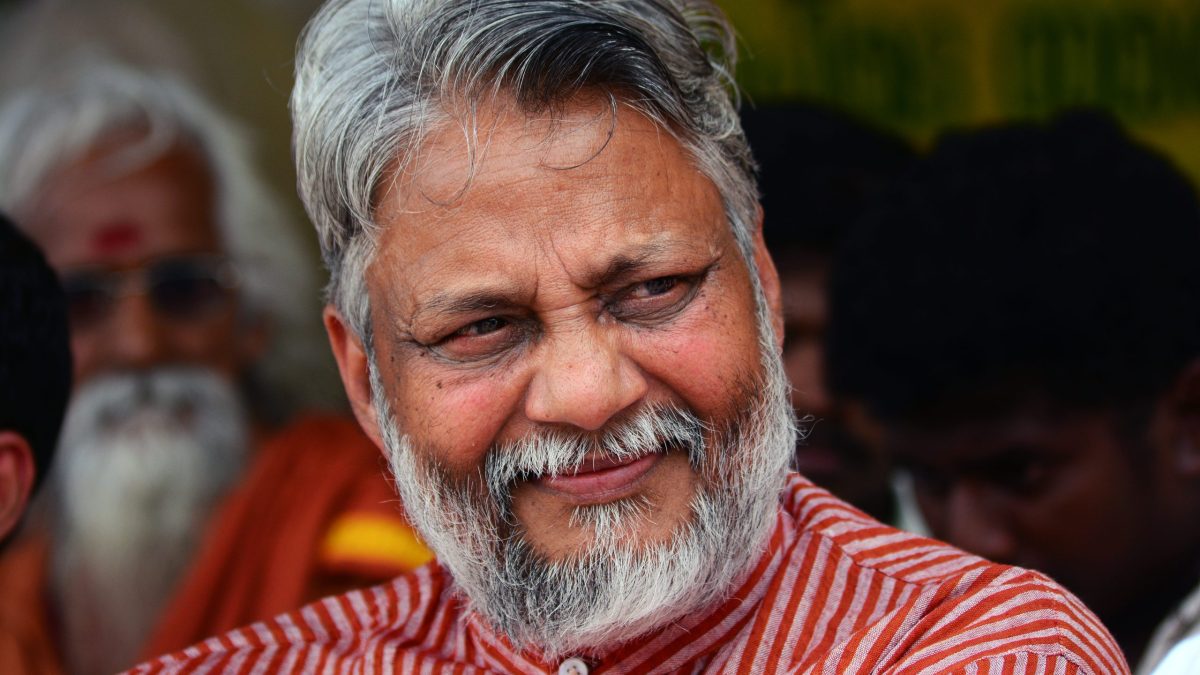 Close-up of Rajendra Singh with grey hair and beard, smiling in a striped red kurta