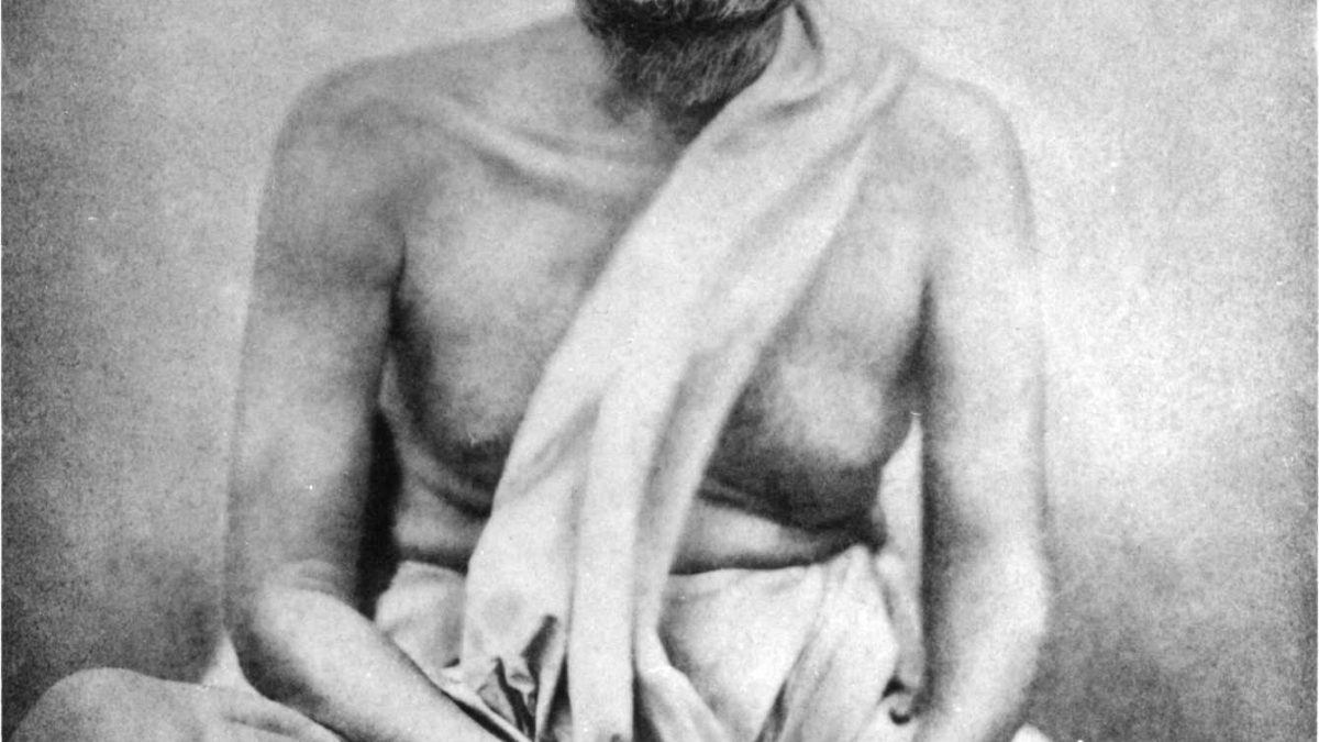 Photograph of Ramakrishna seated cross-legged with his hands folded in his lap