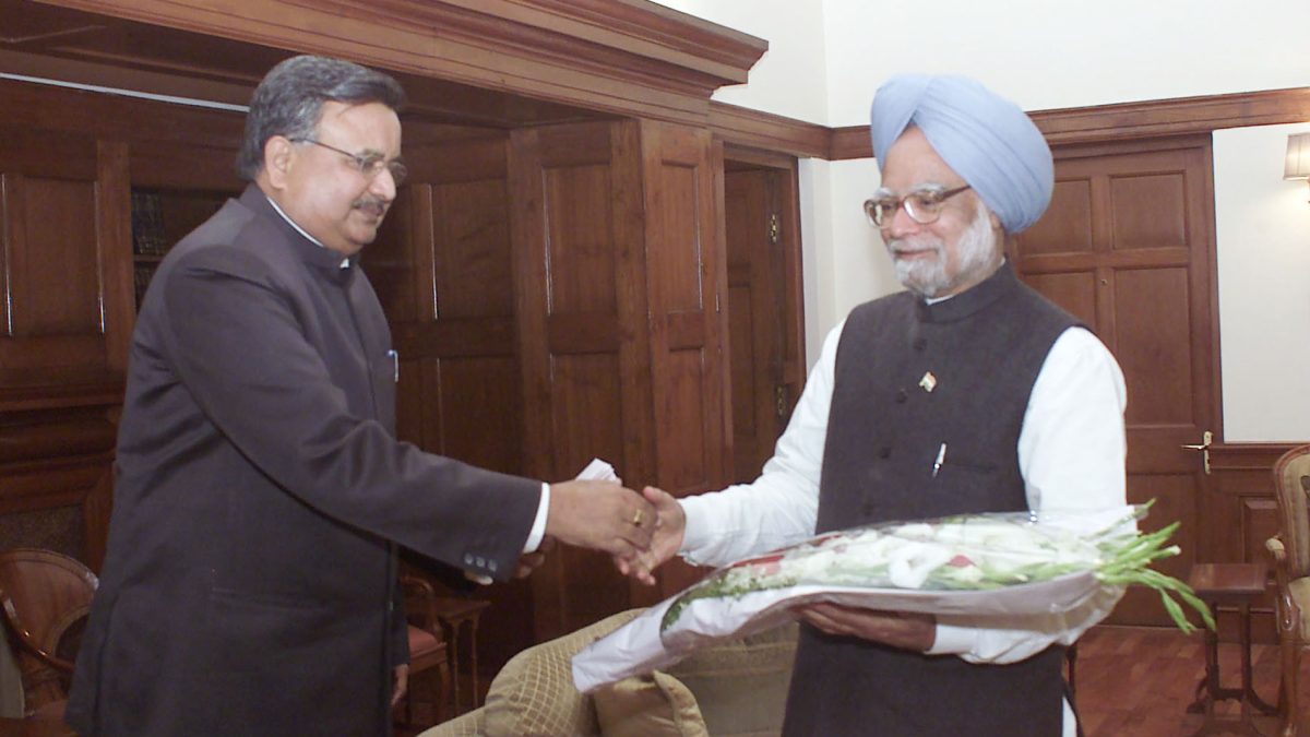 Raman Singh in a dark suit shaking hands with Prime Minister Manmohan Singh