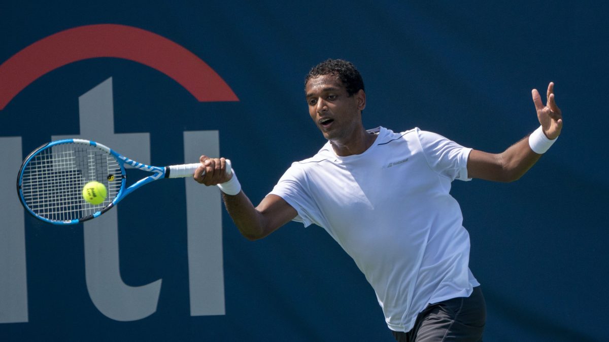 Ramkumar Ramanathan in a white shirt stretching to hit a forehand