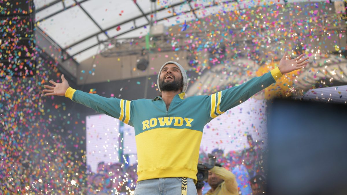 Vijay Deverakonda with his arms outstretched under falling confetti