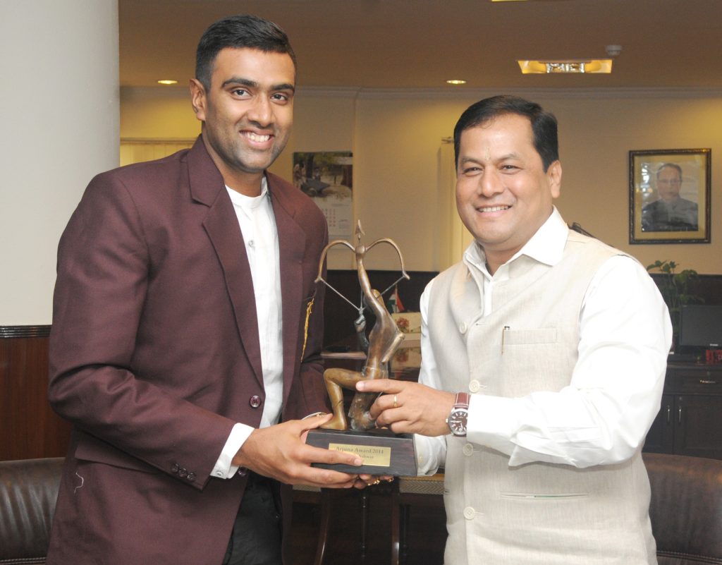 Ravichandran Ashwin in a maroon blazer smiling as he receives the Arjuna Award trophy