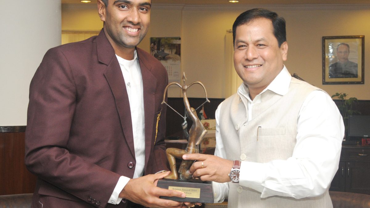 Ravichandran Ashwin in a maroon blazer smiling as he receives the Arjuna Award trophy
