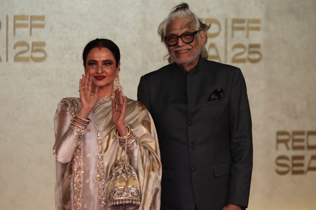 Rekha in a gold sari on a red carpet beside director Muzaffar Ali