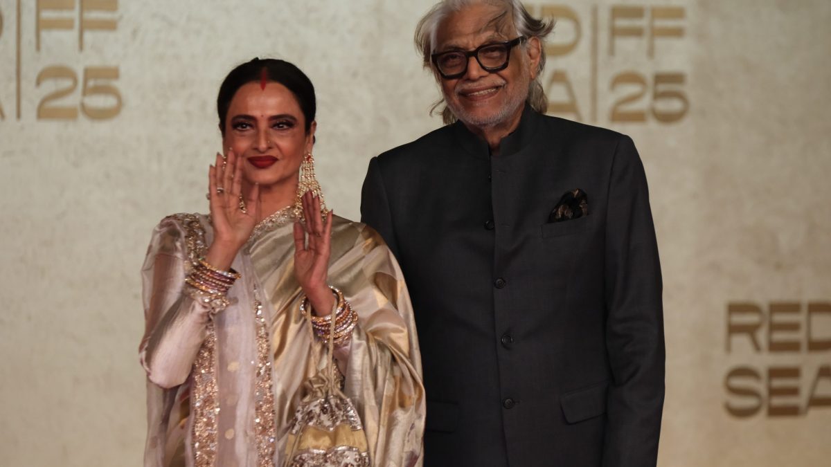 Rekha in a gold sari on a red carpet beside director Muzaffar Ali