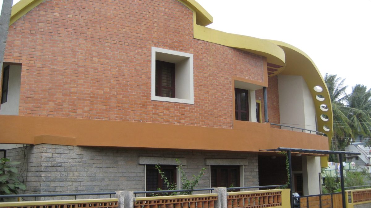 A modern brick house with a curved roof in Mysore