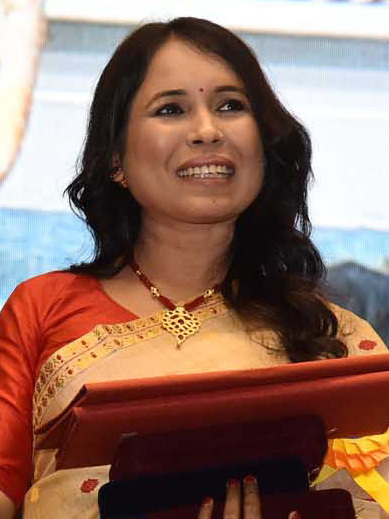 Rima Das in a red and cream sari holding her award