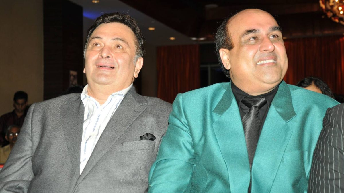 Rishi Kapoor in a grey suit smiling beside Shahid Rafi