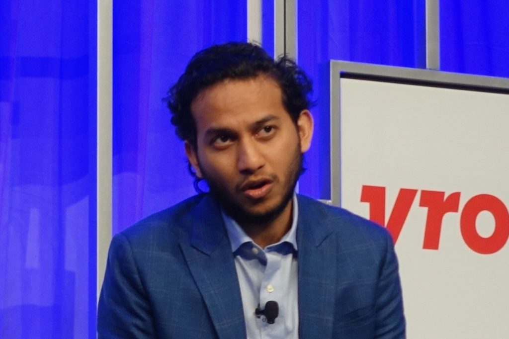 Ritesh Agarwal in a blue blazer speaking on stage at a conference