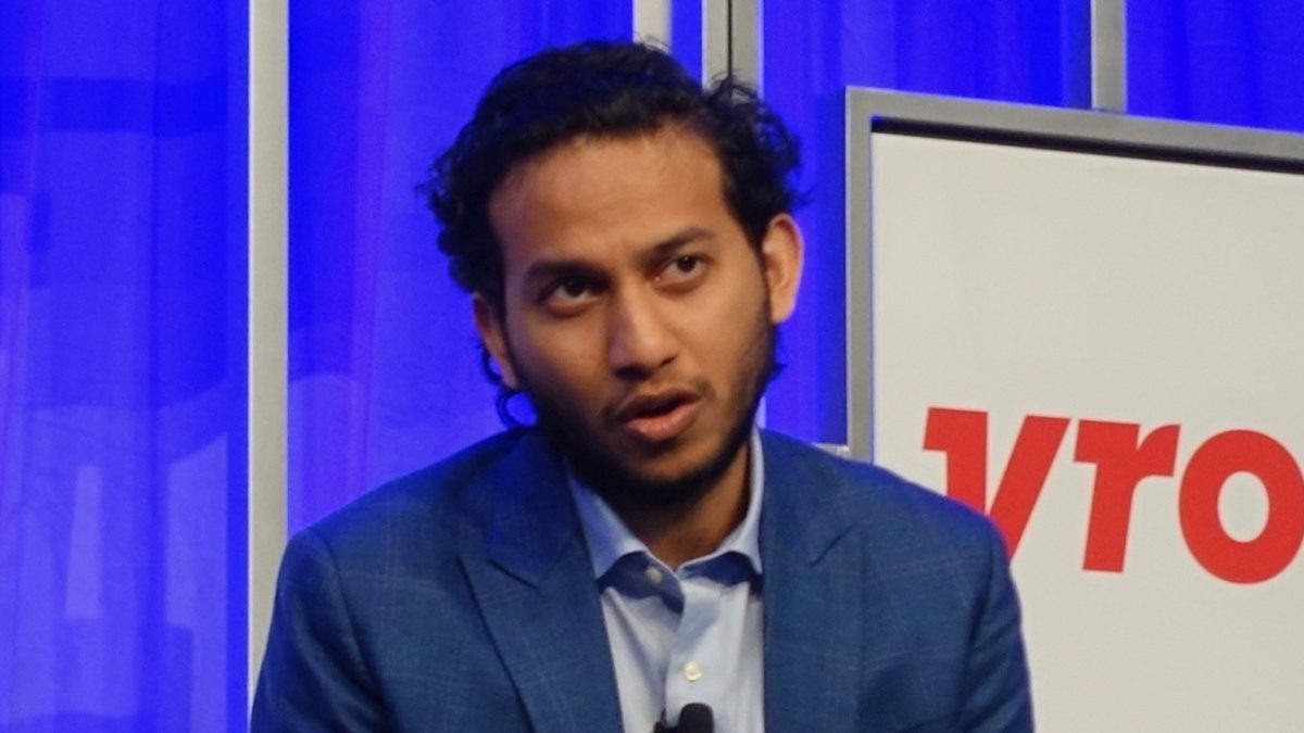 Ritesh Agarwal in a blue blazer speaking on stage at a conference