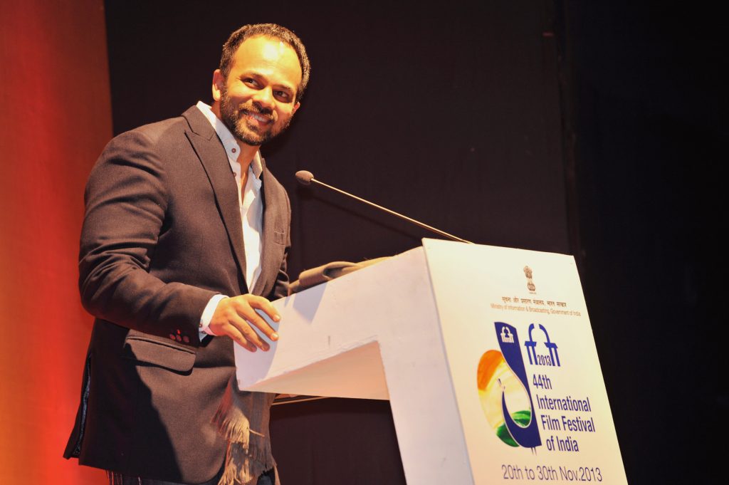 Rohit Shetty in a dark jacket smiling at a lectern at the International Film Festival of India