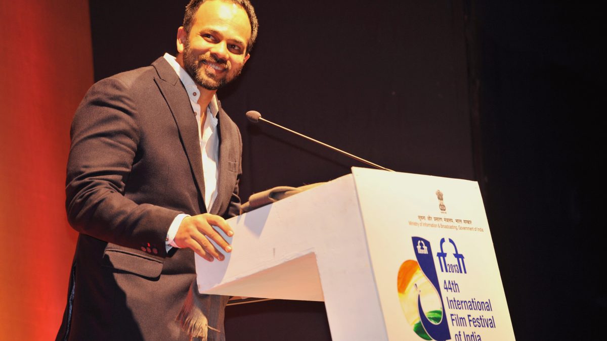 Rohit Shetty in a dark jacket smiling at a lectern at the International Film Festival of India