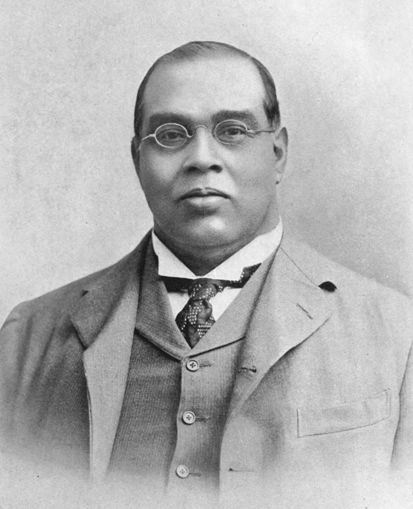 Black-and-white portrait of Romesh Chunder Dutt in glasses, a suit and waistcoat