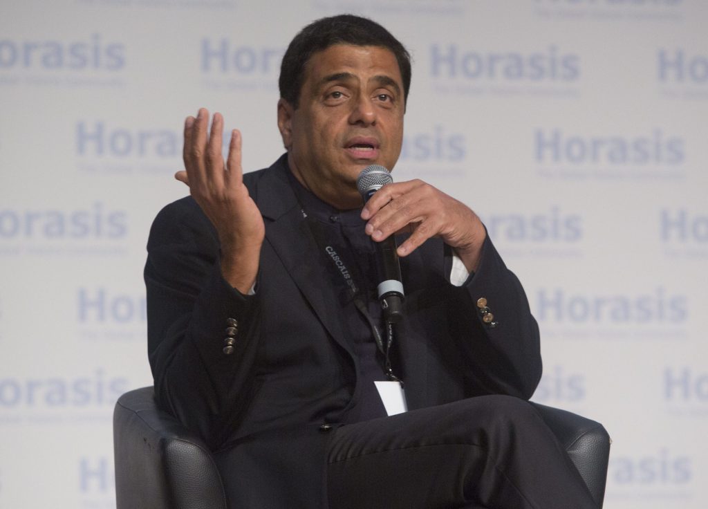 Ronnie Screwvala in a dark jacket seated on stage, gesturing with both hands