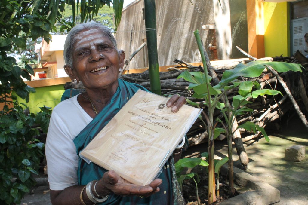 Saalumarada Thimmakka smiling and holding up a certificate outdoors