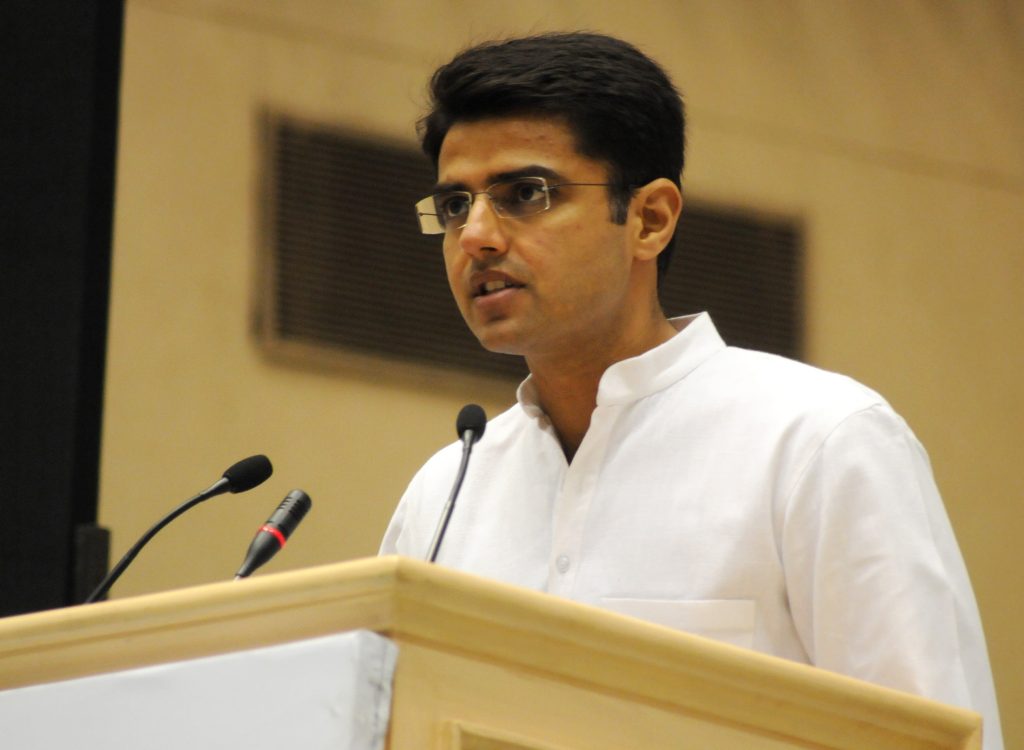 Sachin Pilot in a white kurta speaking at a lectern microphone