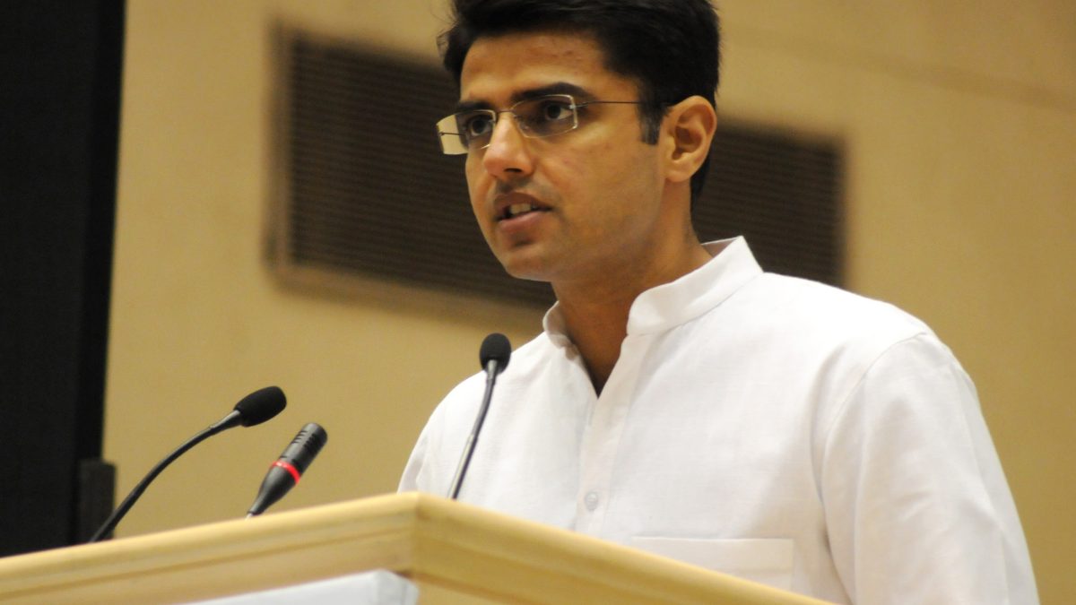 Sachin Pilot in a white kurta speaking at a lectern microphone