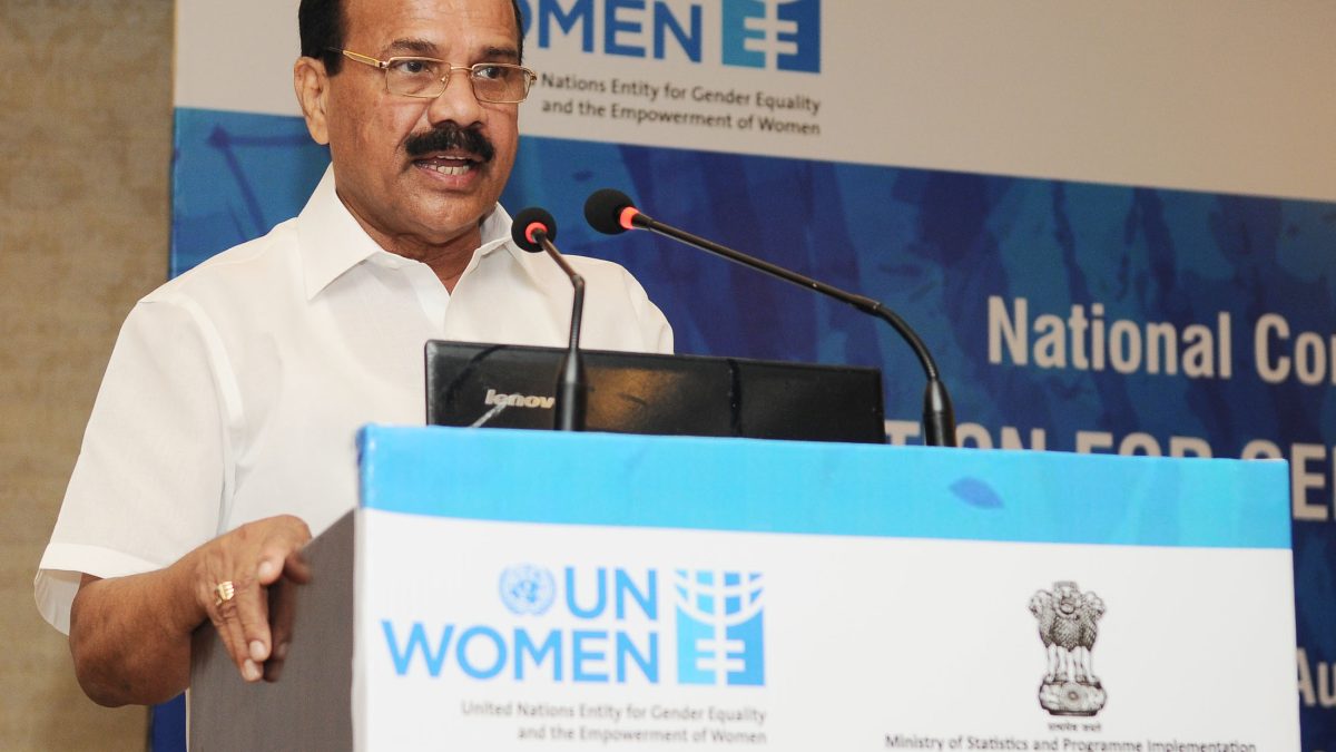 D. V. Sadananda Gowda in a white shirt speaking at a lectern with a UN Women logo
