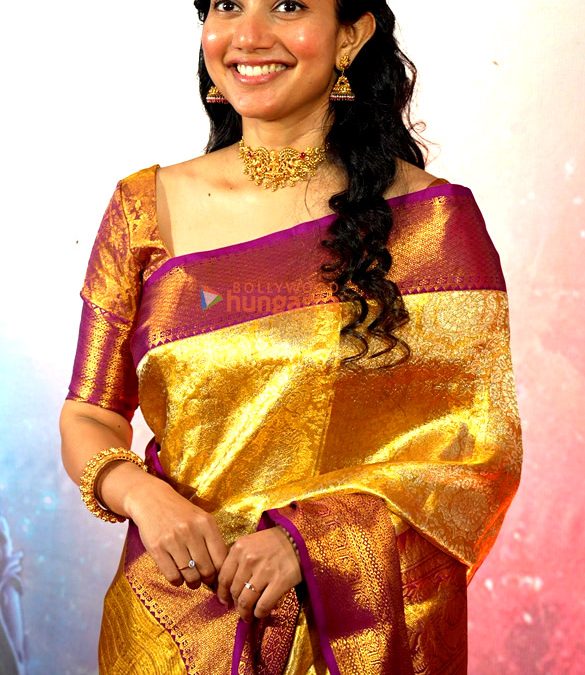 Sai Pallavi in a gold silk saree smiling at a Ramayana event