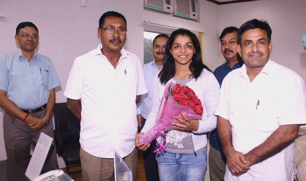 Sakshi Malik holding a bouquet of red roses while meeting Minister of State for Railways Rajen Gohain
