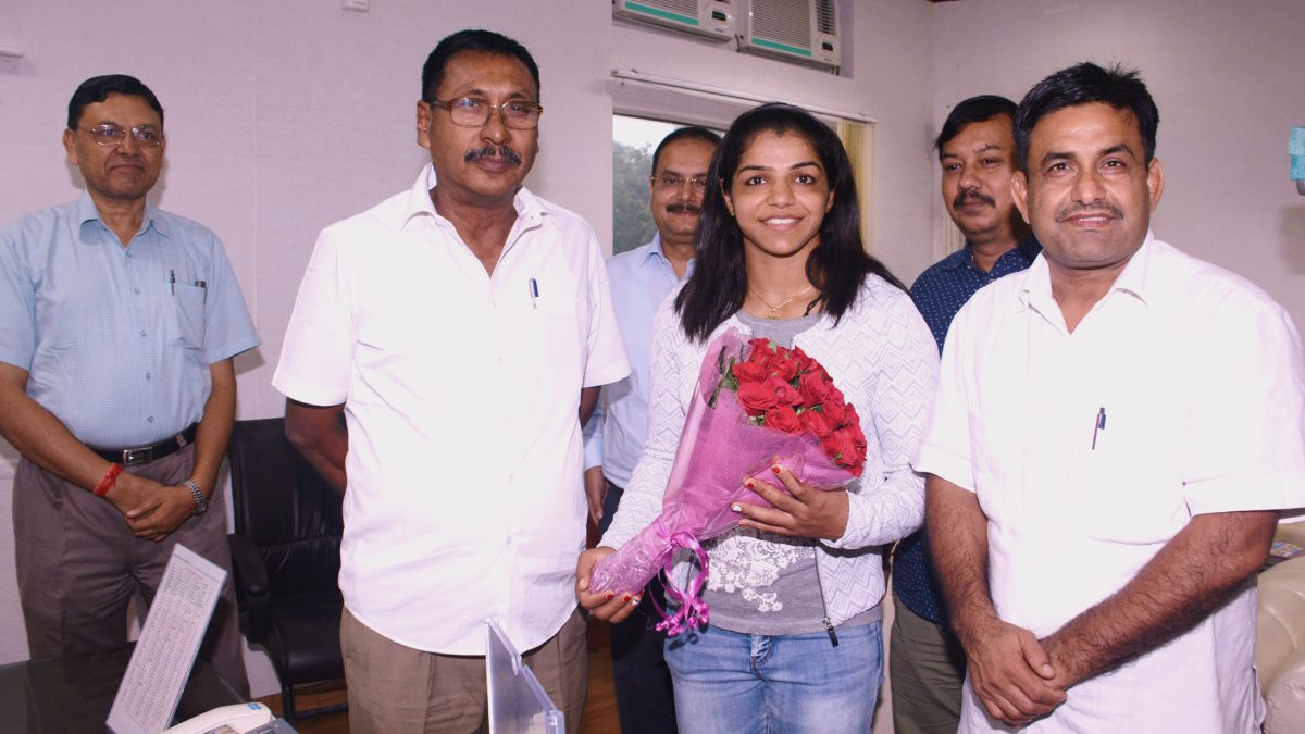 Sakshi Malik holding a bouquet of red roses while meeting Minister of State for Railways Rajen Gohain