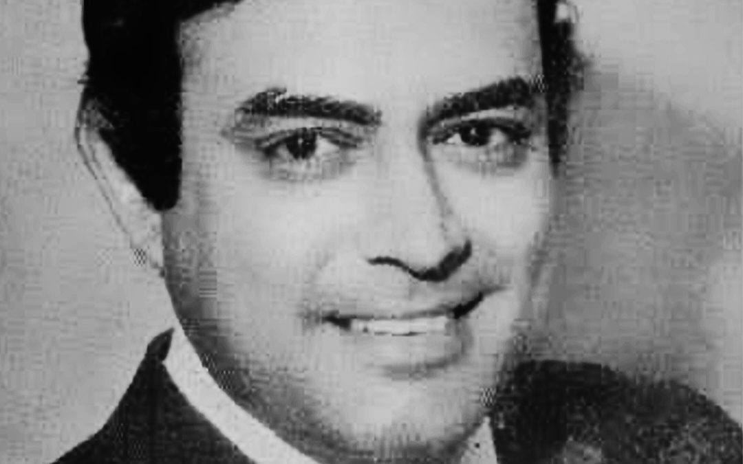 A black-and-white portrait of Sanjeev Kumar in a suit, smiling