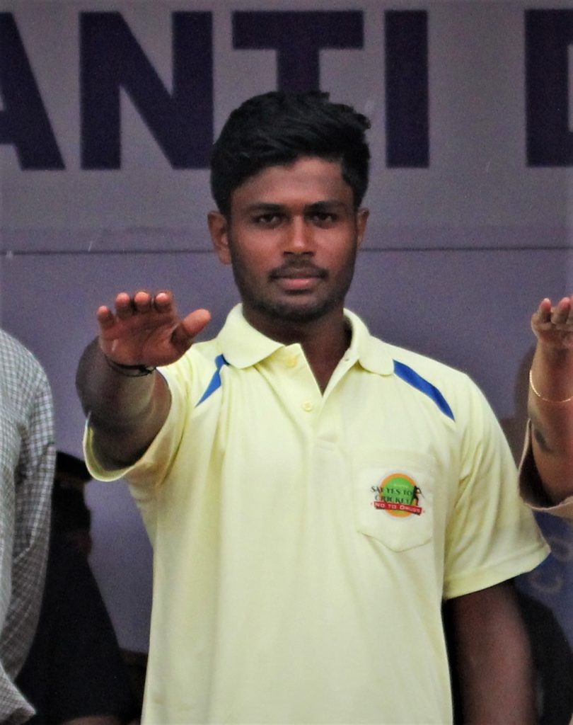 Sanju Samson in a yellow Kerala jersey raising his hand in a huddle
