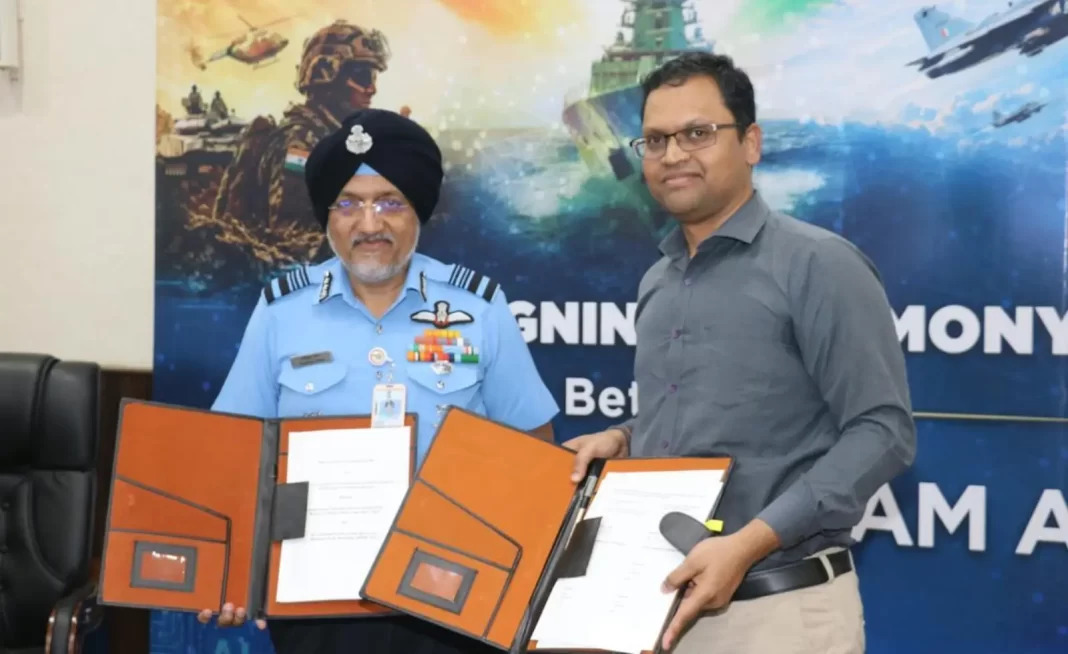 Two men exchange signed memorandum folders at the Sarvam defence AI agreement ceremony