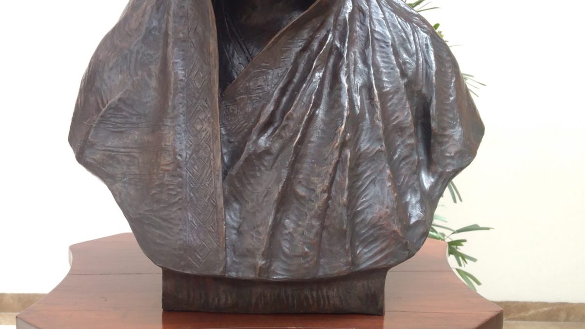 A bronze bust of Savitribai Phule with her sari drawn over her head, on a pedestal