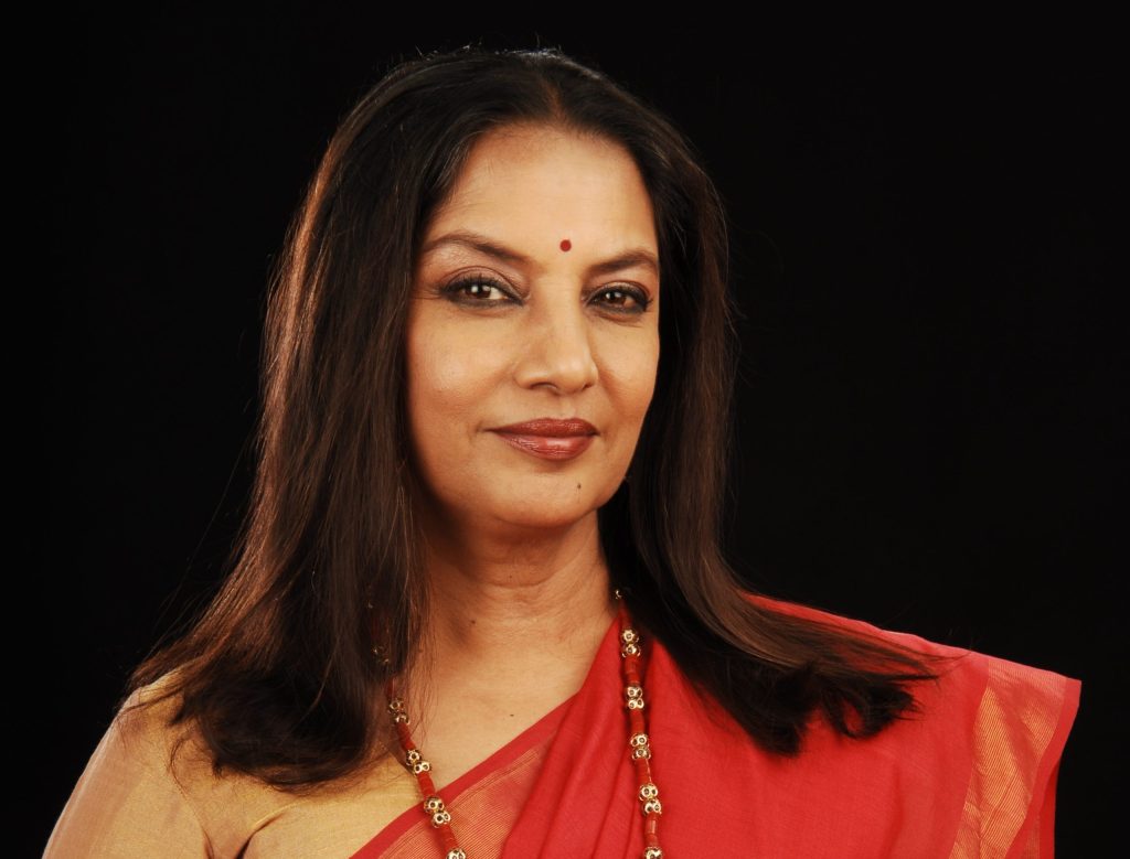 Portrait of Shabana Azmi in a red sari against a black background