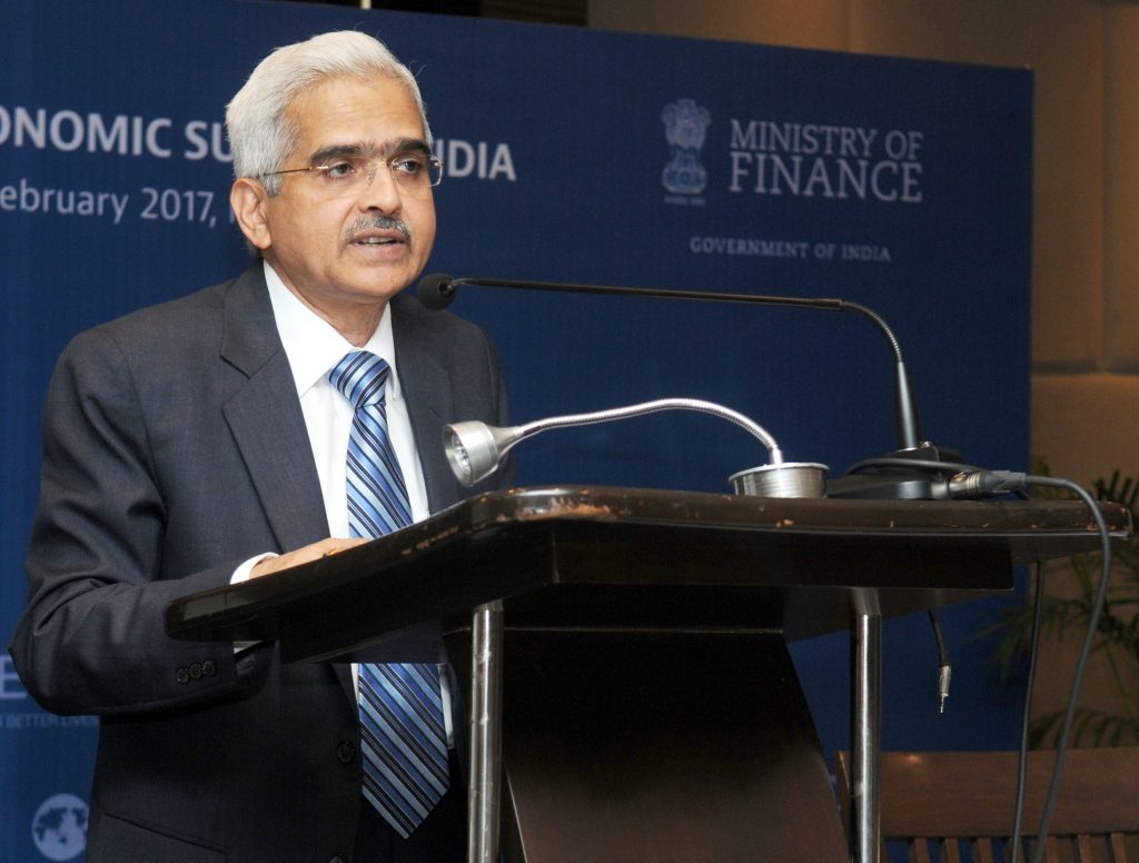 Shaktikanta Das in a dark suit and glasses speaking at a lectern