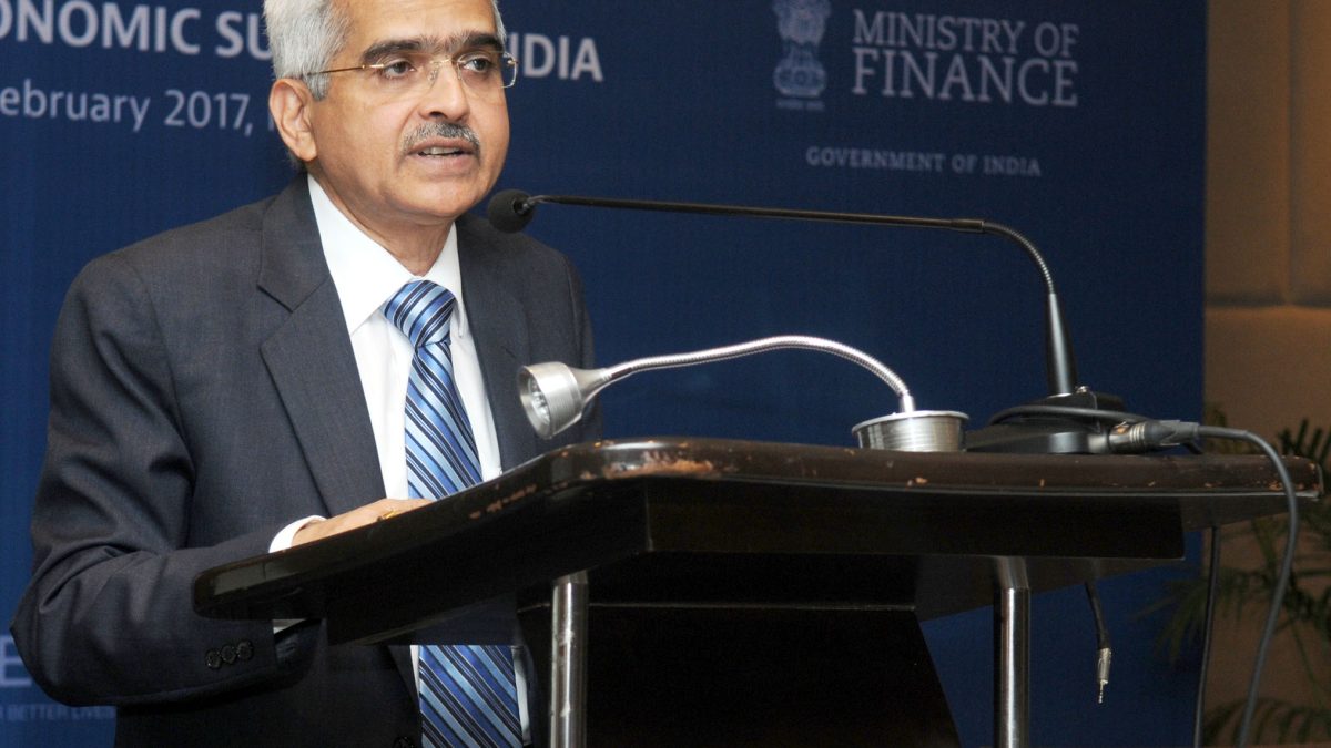 Shaktikanta Das in a dark suit and glasses speaking at a lectern