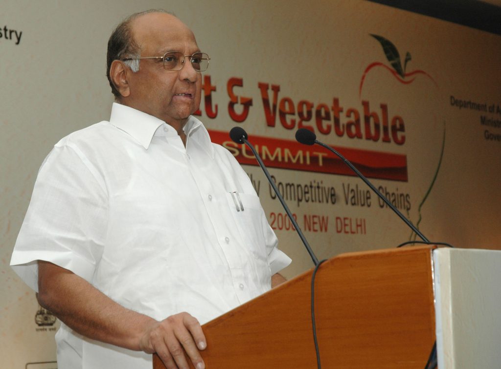 Sharad Pawar in a white shirt speaking at a lectern at a fruit and vegetable summit