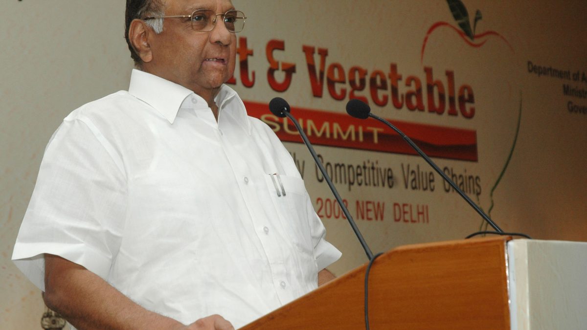 Sharad Pawar in a white shirt speaking at a lectern at a fruit and vegetable summit