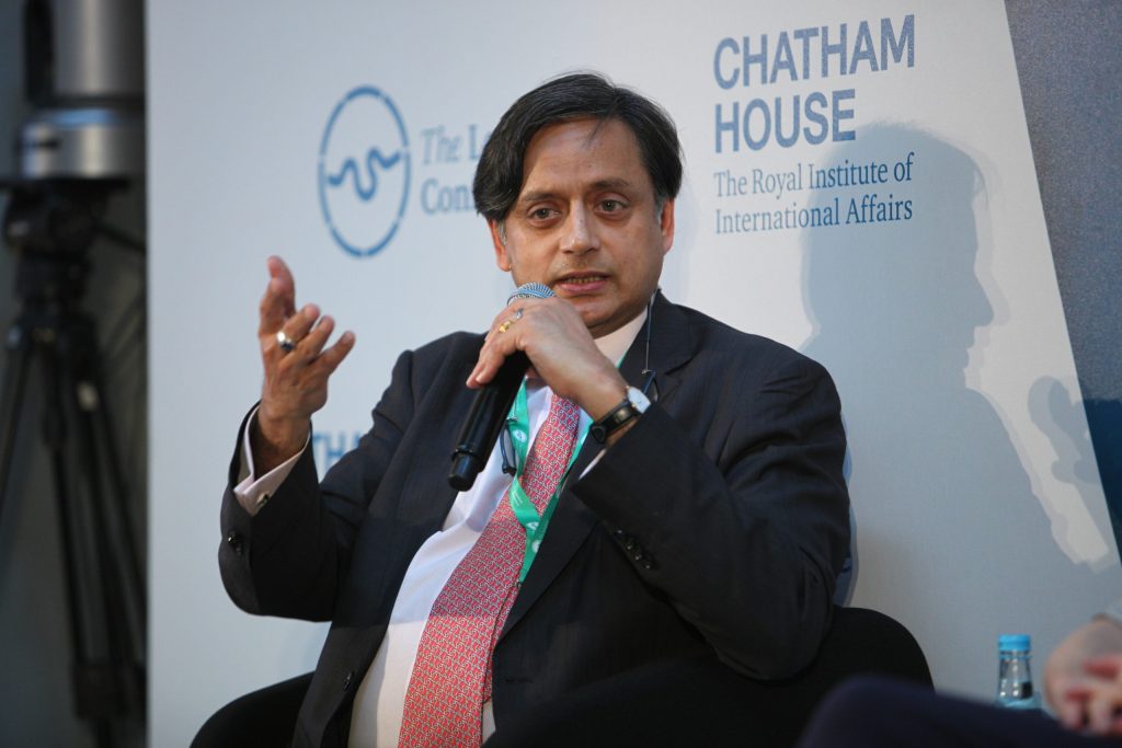 Shashi Tharoor speaking into a microphone at the Chatham House London Conference