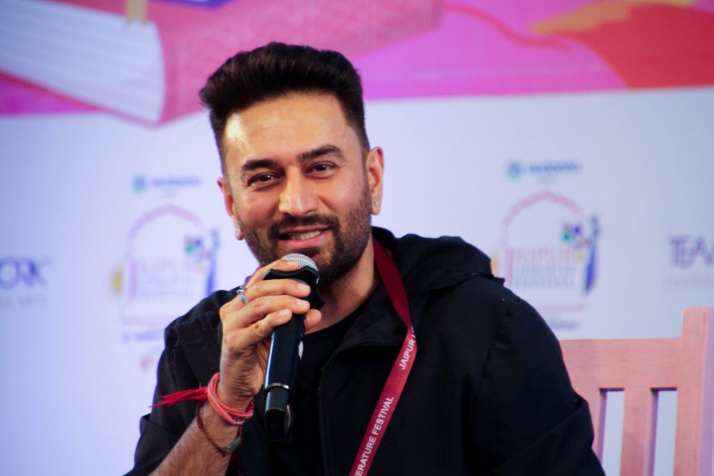 Shekhar Ravjiani with a beard, in a dark jacket, speaking into a microphone