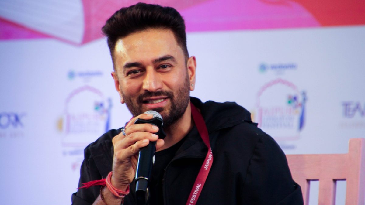 Shekhar Ravjiani with a beard, in a dark jacket, speaking into a microphone