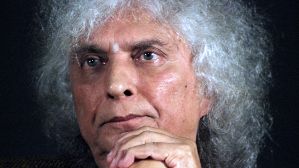 Close-up of Shivkumar Sharma with a halo of white curly hair, hand to his chin