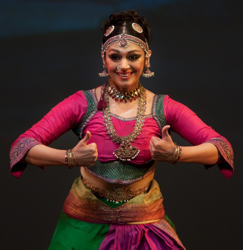 Shobana in a pink and green Bharatanatyam costume, mid-pose on stage