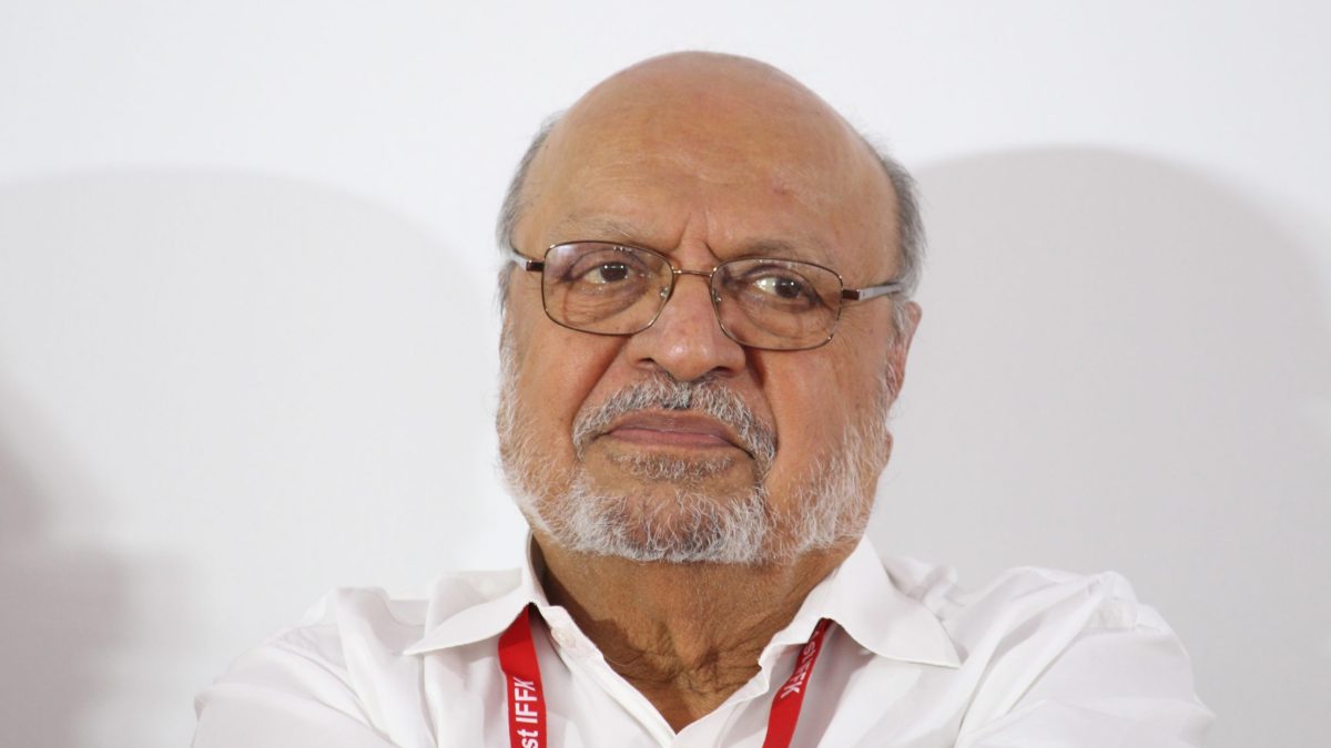 Close-up of Shyam Benegal with a white beard and glasses, wearing a festival lanyard