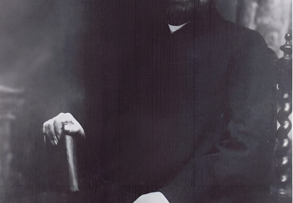 Shyamji Krishna Varma seated in a dark suit, with a beard and glasses